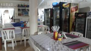 ein Restaurant mit einem Tisch, Stühlen und Sodageräten in der Unterkunft Hotel Delambiance in Koboko