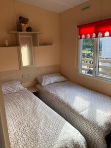 2 Betten in einem kleinen Zimmer mit Fenster in der Unterkunft 73 Glenfinart Park in Dunoon