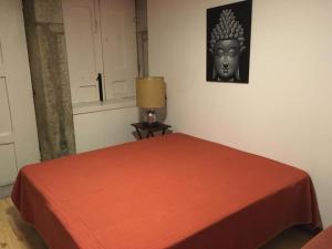 1 dormitorio con 1 cama con máscara en la pared en Casa do Ser Hostel, en Viana do Castelo