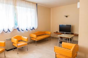 Filottrano的住宿－Hotel Ostello Settecolli Sport，一间配备有橙色椅子和平面电视的等候室