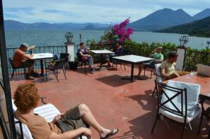 a group of people sitting around tables on a patio at Mikaso Hotel in San Pedro La Laguna