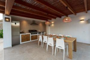 cocina con mesa de madera y sillas blancas en Hort den Pilot, en Sant Rafel de sa Creu