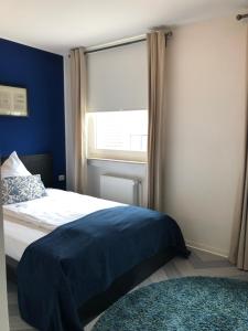 een slaapkamer met een bed met blauwe muren en een raam bij bensons hotel in Aken