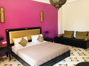 ein Schlafzimmer mit einem Bett und einer rosa Wand in der Unterkunft Le Rubis Oriental in Azib Oulad Lâdem