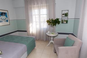 Magnolia - Apartment in Kalamata في كالاماتا: غرفة نوم بسرير وكرسي وطاولة