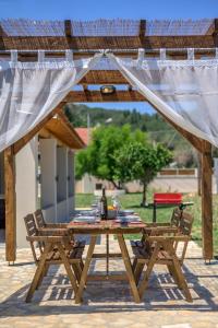 drewniany stół i dwa krzesła pod pergolą w obiekcie Villa Veneto Luxury holidays w mieście Melíssia