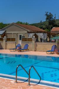 basen z dwoma niebieskimi krzesłami obok domu w obiekcie Villa Veneto Luxury holidays w mieście Melíssia