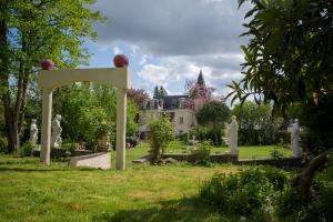 einen Garten mit Statuen und ein Haus im Hintergrund in der Unterkunft Le Madrigal in Mamers