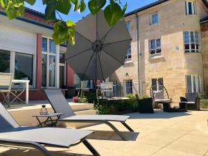 - une terrasse avec 2 chaises et un parasol dans l'établissement Maison d'hôtes La Villa des Ducs Bar-le-Duc, à Bar-le-Duc