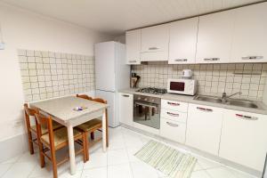 kuchnia z białymi szafkami, stołem i kuchenką mikrofalową w obiekcie Veneziacentopercento Picenin Apartment w Wenecji