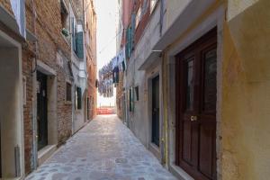 an empty alley with a brown door and buildings at Veneziacentopercento Arsenale Apartment in Venice