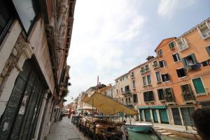 a street with buildings and a boat on a canal at Veneziacentopercento Arsenale Apartment in Venice +2 photos