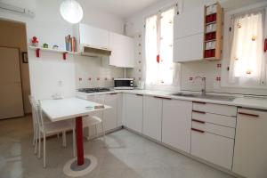 uma cozinha com armários brancos e uma pequena mesa em Veneziacentopercento Arsenale Apartment em Veneza