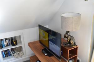 a television on a wooden table with a lamp at Clouds B&B in Kilmuir