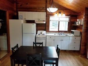 cocina con mesa y nevera blanca en Lake Texoma Camping Resort Cabin 1, en Willow Spring