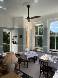 uma sala de jantar com mesas, cadeiras e janelas em The Devonian em Ilfracombe