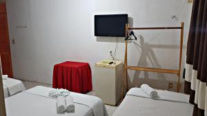 a room with two beds and a tv on a wall at Pousada Manaíra Buena Playa in João Pessoa
