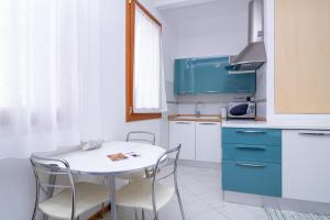 eine kleine Küche mit einem weißen Tisch und Stühlen in der Unterkunft Veneziacentopercento Corderie Apartment in Venedig