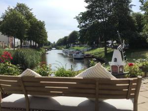 a bench sitting next to a river with boats in it at Hoffmanns Holsteinisches Haus in Friedrichstadt