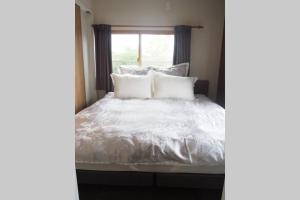 un letto con lenzuola e cuscini bianchi accanto a una finestra di Harbour Inn & Suites 201 a Niigata