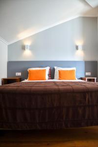 - un grand lit avec 2 oreillers orange dans l'établissement Hotel Casa da Nora, à Leiria