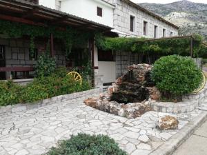 a stone patio with a fountain in front of a building at Vinarija Andjusic in Dračevo