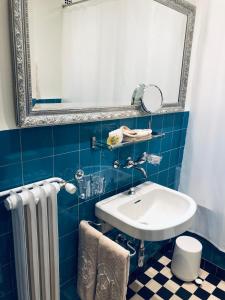 uma casa de banho em azulejos azuis com um lavatório e um espelho em Hotel Adriatica em Genebra