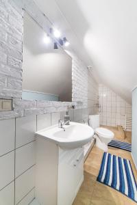 a white bathroom with a sink and a toilet at Apartamenty Mewa in Rewa