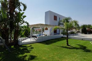 a white house with a yard with a palm tree at Chara Sensory Luxury Villa, By ThinkVilla in Panormos Rethymno