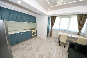 Una cocina con gabinetes azules y una mesa y sillas. en Sweet Luxury - CentralPark, en Galaţi