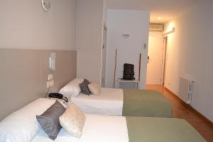 Cette chambre comprend deux lits et une télévision. dans l'établissement Duerming Villa De Sarria Hotel, à Sarria