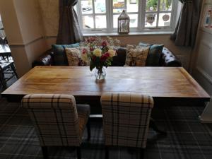 a wooden table with a vase of flowers on it at Woolpack Inn in Chichester