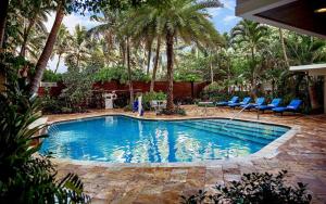 フォート・ローダーデールにあるSun Tower Hotel & Suites on the Beachの青い椅子とヤシの木がある大きなスイミングプール
