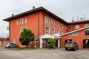 un gran edificio rojo con coches estacionados en un estacionamiento en Hotel Villa Strassoldo "Ex Attianese Hotel Restaurant" en Cervignano del Friuli