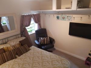 a bedroom with a bed and a chair and a television at The little garden hoose in Inverness +10 photos