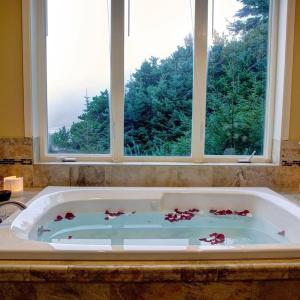 eine Badewanne mit Blumen und einem Fenster in der Unterkunft Starfish Point in Newport