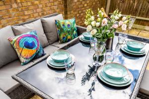 a table with plates and glasses and flowers on a couch at Burgess Beach House in Caister-on-Sea