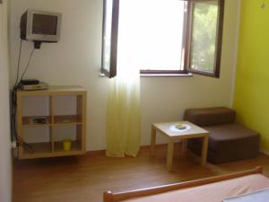 a living room with a tv and a chair and a table at Villa Welcome in Vrboska