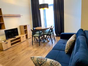 uma sala de estar com um sofá azul e uma mesa em Boutique Magenta Gold Apartment em Sófia