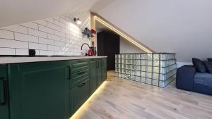 uma cozinha com armários verdes e um sofá azul em Lux Apartment Loft em Polanica-Zdrój