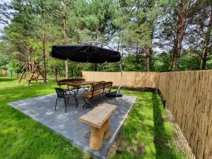 a picnic table and bench with an umbrella in a yard at Bajka Domek na Roztoczu in Bondyrz
