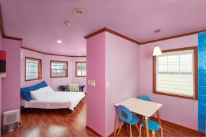Cette chambre rose comprend un lit, une table et des chaises. dans l'établissement CHAEUL Pension, à Pyeongchang