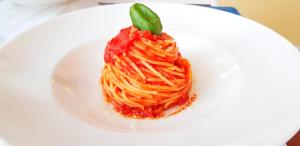a white plate with a pasta dish with a green leaf on it at Hotel Villa Adriana in Monterosso al Mare