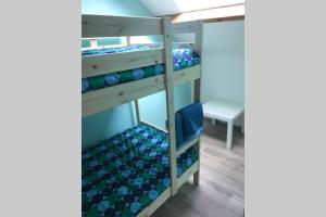 Ce lit superposé se trouve dans un dortoir doté d'une chaise bleue. dans l'établissement Petite maison à la campagne, à Couvin