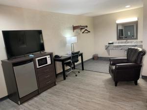 ein Hotelzimmer mit einem TV, einem Stuhl und einem Schreibtisch in der Unterkunft Crescent Park Motel & Suites in Littlefield