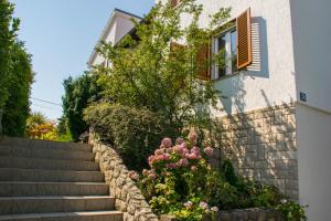 a house with stairs and flowers in front of it at Apartments White & Green in Malinska in Malinska