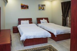 a bedroom with two beds with white sheets and a table at Najd Peak By Quiet Rooms in Riyadh