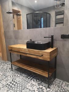 a bathroom with a black sink on a wooden counter at GOLDEN ROOMS blisko Energylandii in Zator