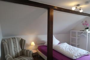 a bedroom with a canopy bed and a chair at Landpension zur Hainbuche in Romrod