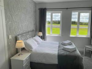 a bedroom with a bed and two windows at Gurraun House in Kilkee